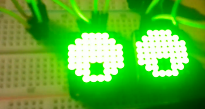 "two led matrices with green lights illustrating eyes"